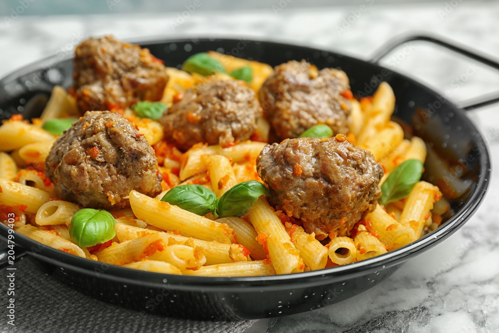 Pasta with meatballs and tomato sauce on frying pan, closeup