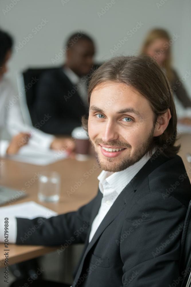 Smiling young businessman in suit looking at camera at meeting, head shot portrait of successful executive team leader, business professional, board member or conference participant, vertical view Smiling young businessman in suit looking at camera at meeting, head shot portrait of successful executive team leader, business professional, board member or conference participant, vertical view