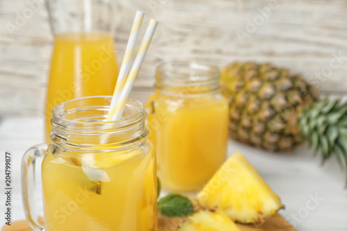 Mason jars with delicious pineapple juice on table