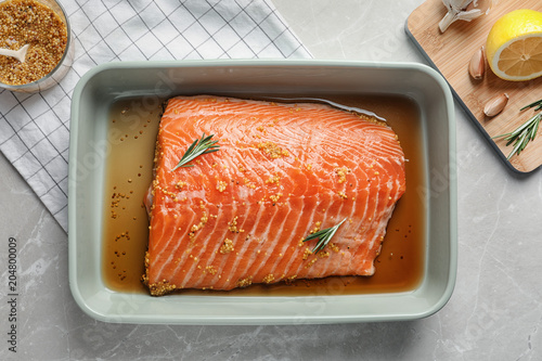 Marinated salmon fillet in dish on table, top view