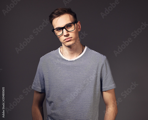Fashion serious man posing in trendy glasses in strip casual shirt on grey background. Toned portrait with empty copy space © nastia1983