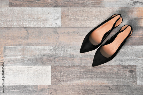 Pair of female shoes on wooden background, top view