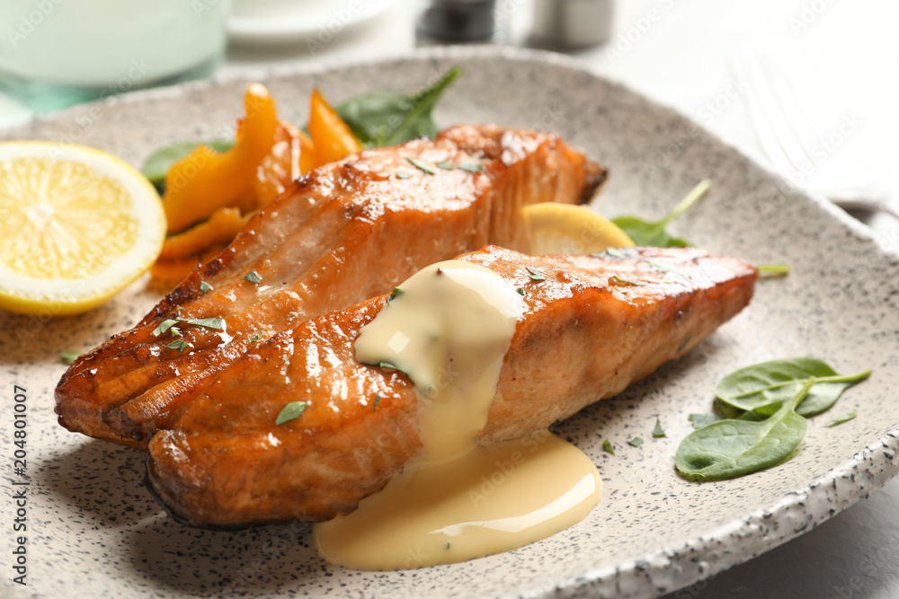 Tasty cooked salmon with sauce on plate, closeup Tasty cooked salmon with sauce on plate, closeup
