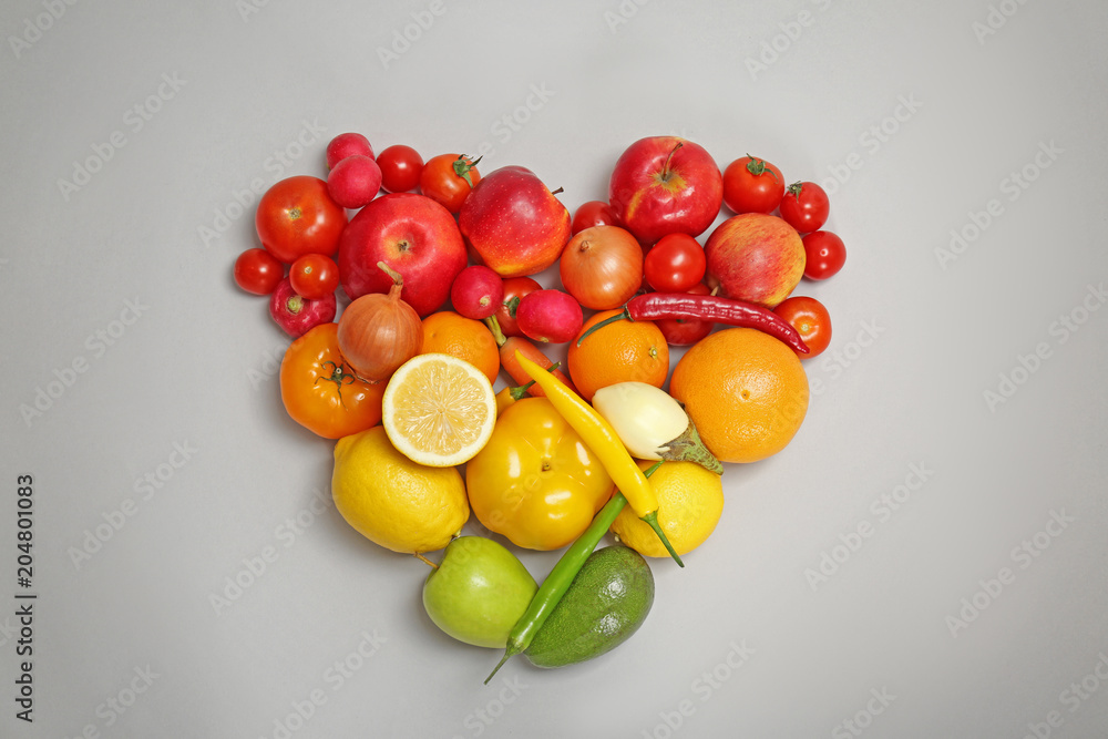 Heart made of ripe fruits and vegetables in rainbow colors on grey background, top view Heart made of ripe fruits and vegetables in rainbow colors on grey background, top view