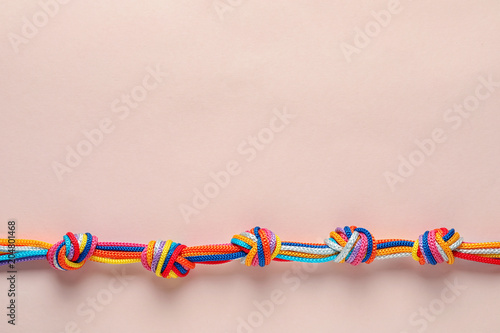 Colorful ropes tied together with many knots on light background, top view. Unity concept