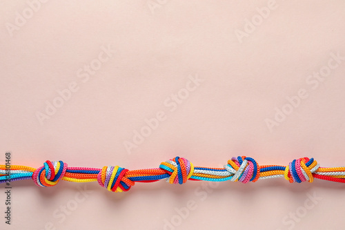 Photography Colorful ropes tied together with many knots on light background, top view