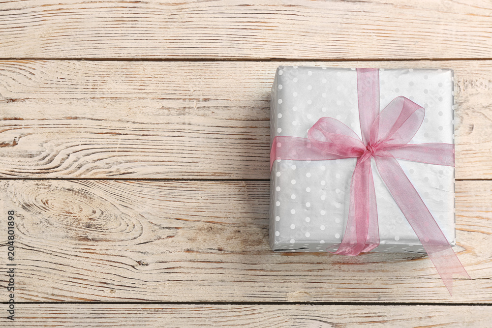 Elegant gift box with bow on wooden background, top view