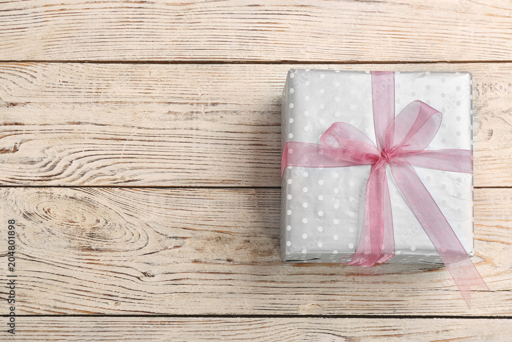 Elegant gift box with bow on wooden background, top view Elegant gift box with bow on wooden background, top view