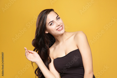 Portrait of beautiful model with gorgeous curly hair on color background