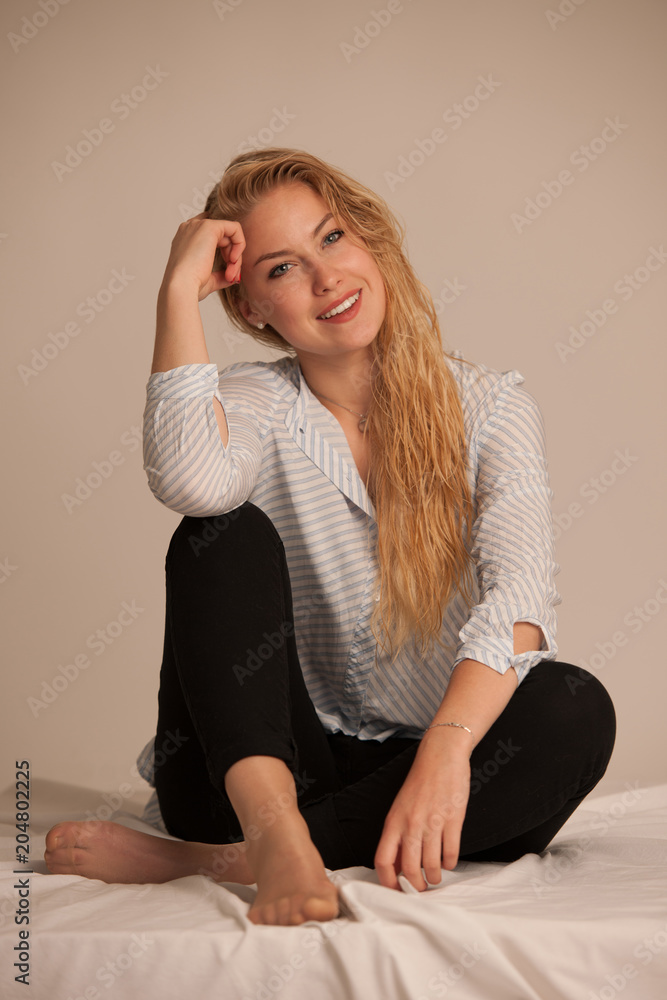 Beautiful young blond woman stting on bed Beautiful young blond woman stting on bed