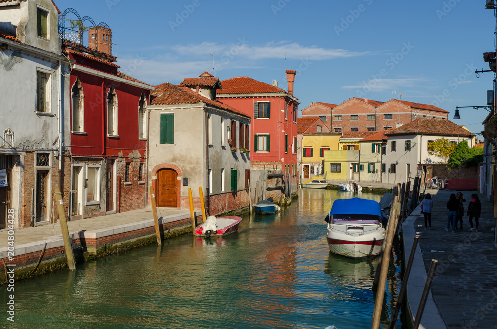 Venetian canal with boats docked on the Murano island