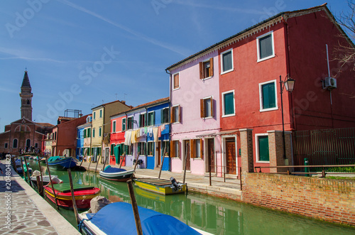 Houses and church on the canal with boats docked at Burano near Venice.