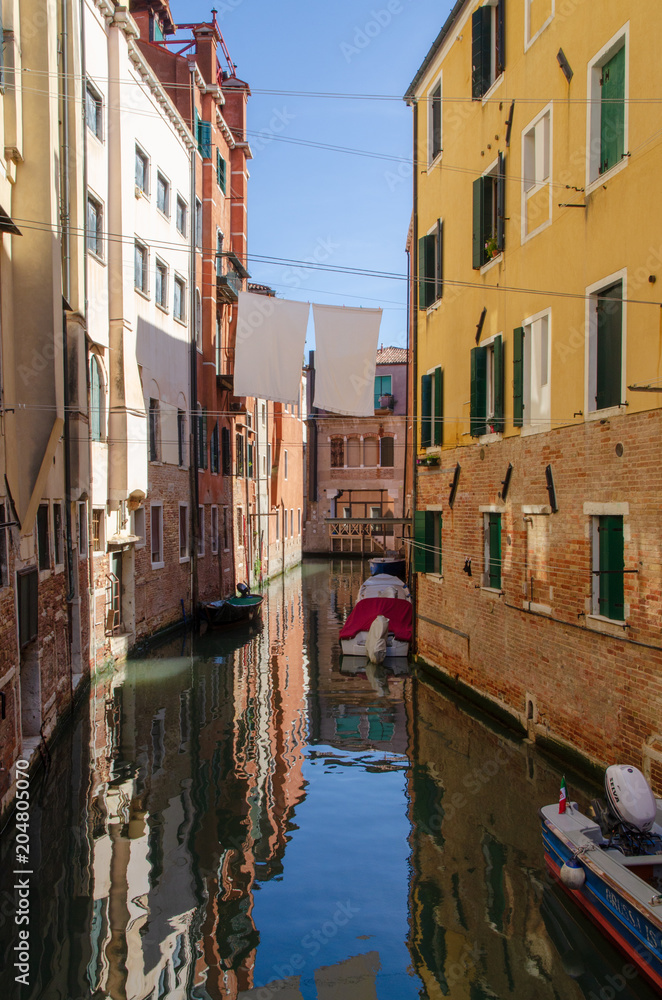 Venetian canal with boats and reflections