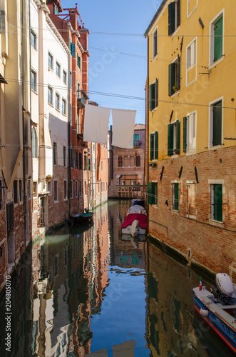 Venetian canal with boats and reflections