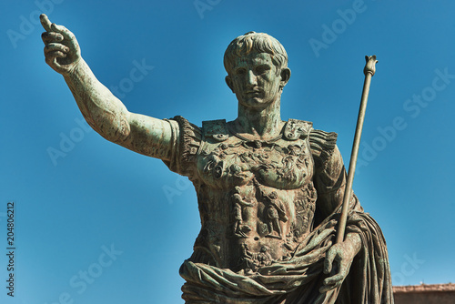 Fotografie Rome, Bronze statue of emperor Caesar Augustus, Forum of Augustus in the backgro