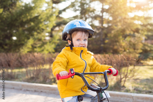 Child boy on a bicycle and helmet in the park in summer. Three years old kid Boy cycling outdoors in safety helmet in sunny weather.