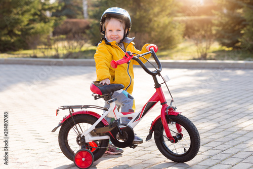 Child boy on a bicycle and helmet in the park in summer. Three years old kid Boy cycling outdoors in safety helmet in sunny weather. © uv_group