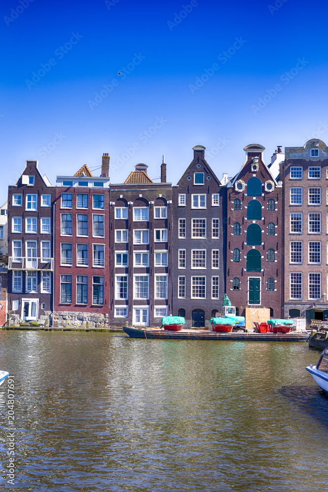 Europe Travel Concepts and Ideas. Row of Traditional Ancient Houses At Damrak Canal in the Capital of The Netherlands in Amsterdam