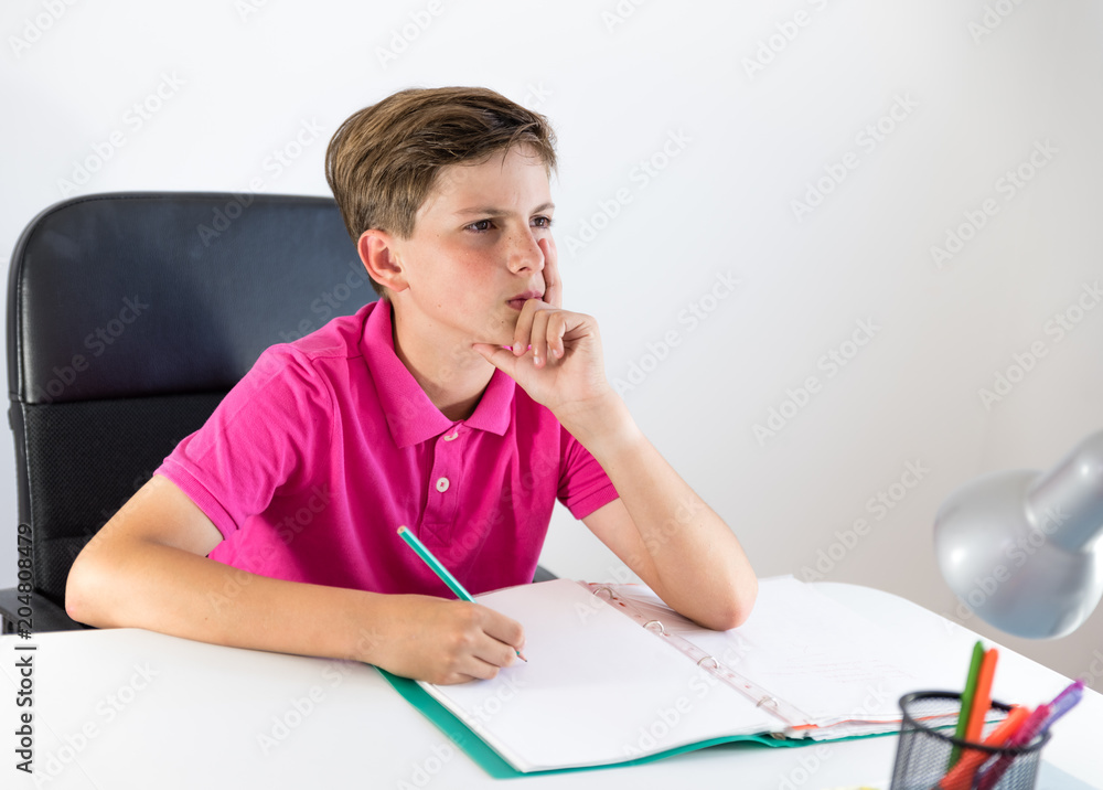 boy doing his homework, thinking the right answer on white background boy doing his homework, thinking the right answer on white background