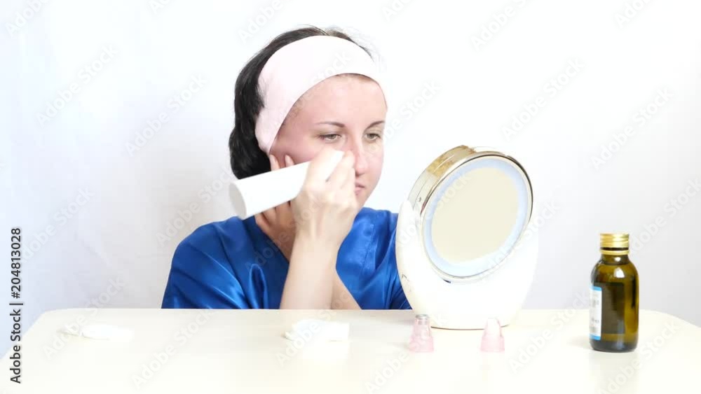 A girl with a device performs microdermabrasion of the skin of the face on a white background. The concept of beauty and skin care. A girl with a device performs microdermabrasion of the skin of the face on a white background. The concept of beauty and skin care.