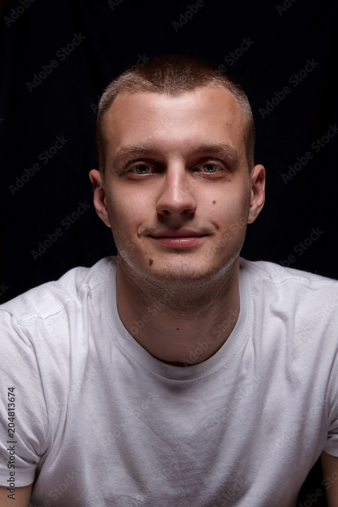 Handsome young caucasian man. In white t-shirt. Smile.Emotion. On black background.Portrait Handsome young caucasian man. In white t-shirt. Smile.Emotion. On black background.Portrait