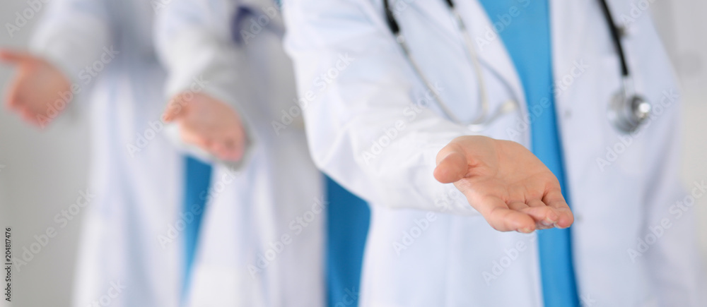 Group of medicine doctors offering helping hand for shaking hand or saving life closeup. Partnership and trust concept in health care or medical cure Group of medicine doctors offering helping hand for shaking hand or saving life closeup. Partnership and trust concept in health care or medical cure