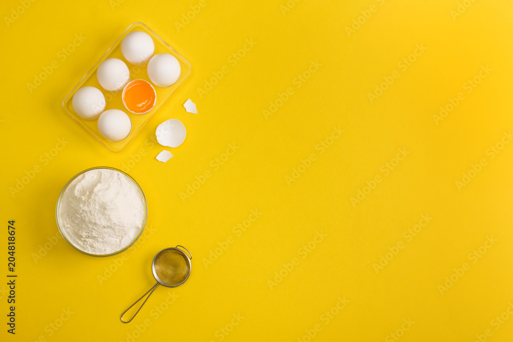 Baking flat lay background with eggs floor sieve on yellow