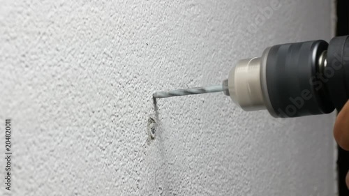 Close-up View of Spinning Metal Spiral electric Drill Bit on the concrete cement white wall