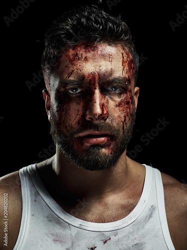 A strong, a serious, muscular man in a white t-shirt is worth and looks in camera. He's got the beard on the face and different emotions