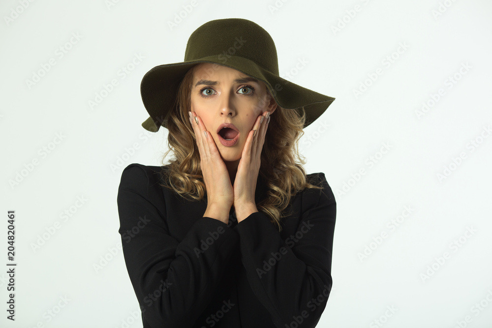 beautiful young girl in a hat on a white background with an amazed face