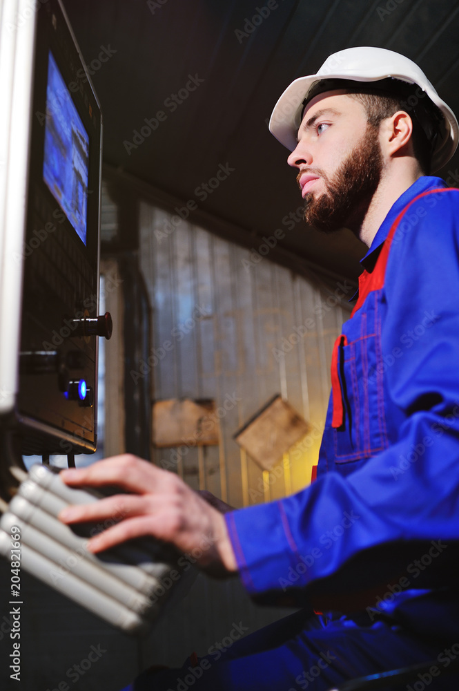 A man in a white construction helmet behind a crane control panel