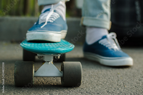 Man in blue skate shoes skateboarding in the park. Front view. The concept of city travelling  vlogging  modern lifestyle