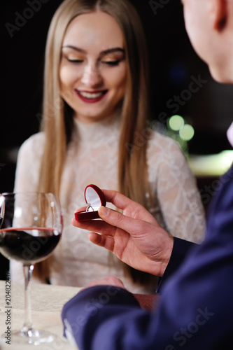 guy doing the girl proposal in restaurant. man gives a woman an engagement ring