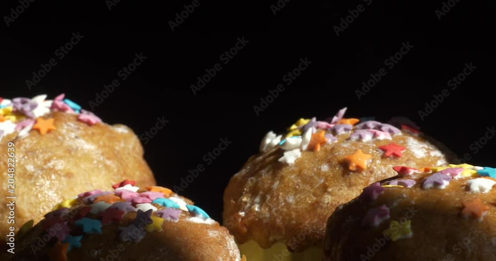 Easter cakes with a colored sprinkle stand in a row on a black background