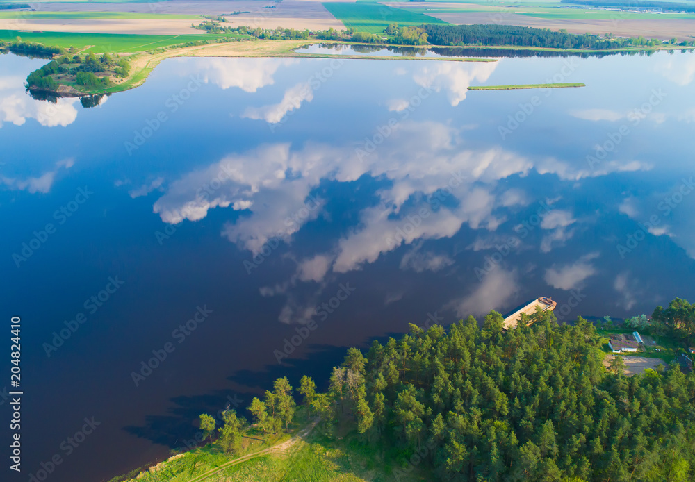 Aerial landscape of lake with calm water and reflection of white clouds