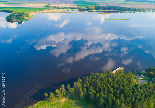 Aerial landscape of lake with calm water and reflection of white clouds