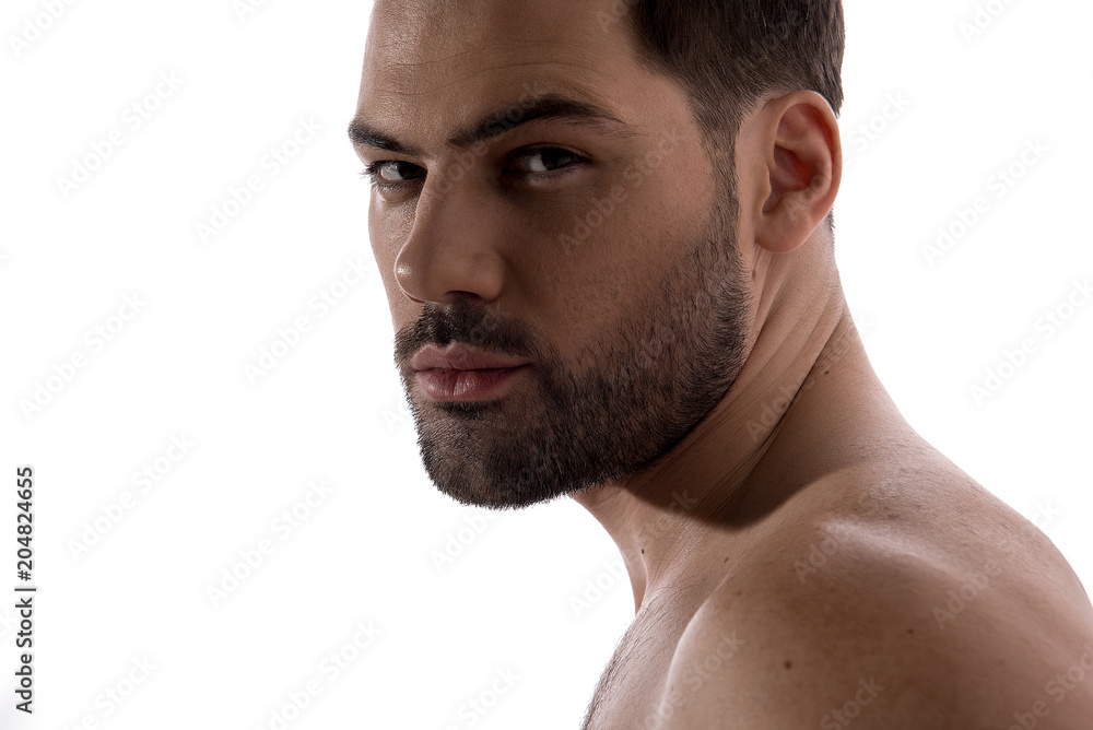 Beauty concept. Close up of face of pleasant shirtless bristled guy is standing and looking at camera thoughtfully. Isolated on light background Beauty concept. Close up of face of pleasant shirtless bristled guy is standing and looking at camera thoughtfully. Isolated on light background