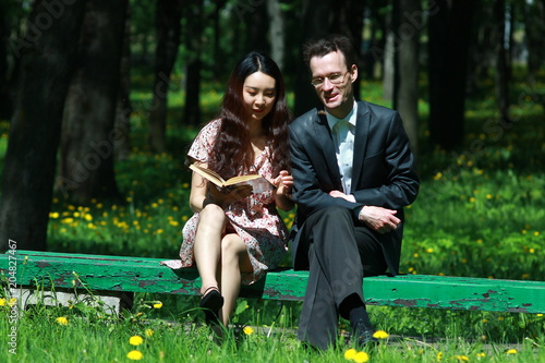 Пара, читающая книгу на скамейке в парке © heshixin