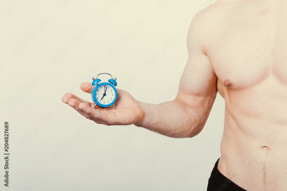 Fototapeta premium healthcare fitness Time and taking care of yourself concept. Man holding alarm over white background.