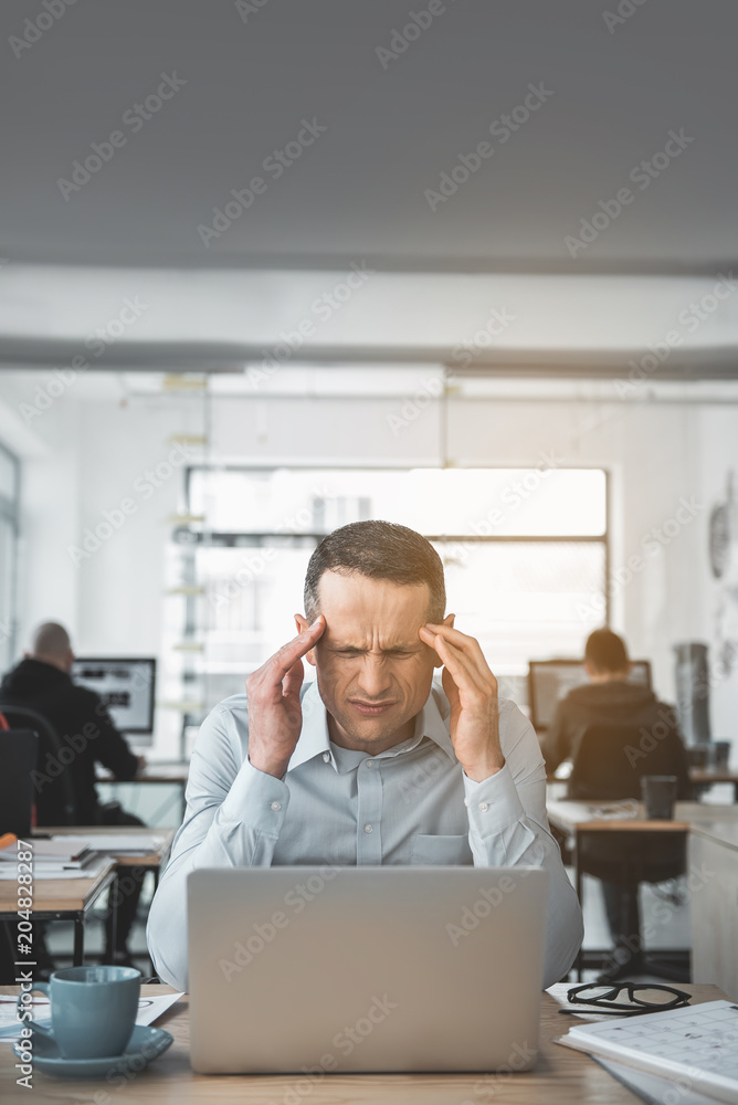 Obraz na plátně Portrait of sad businessman feeling pain in head while using laptop