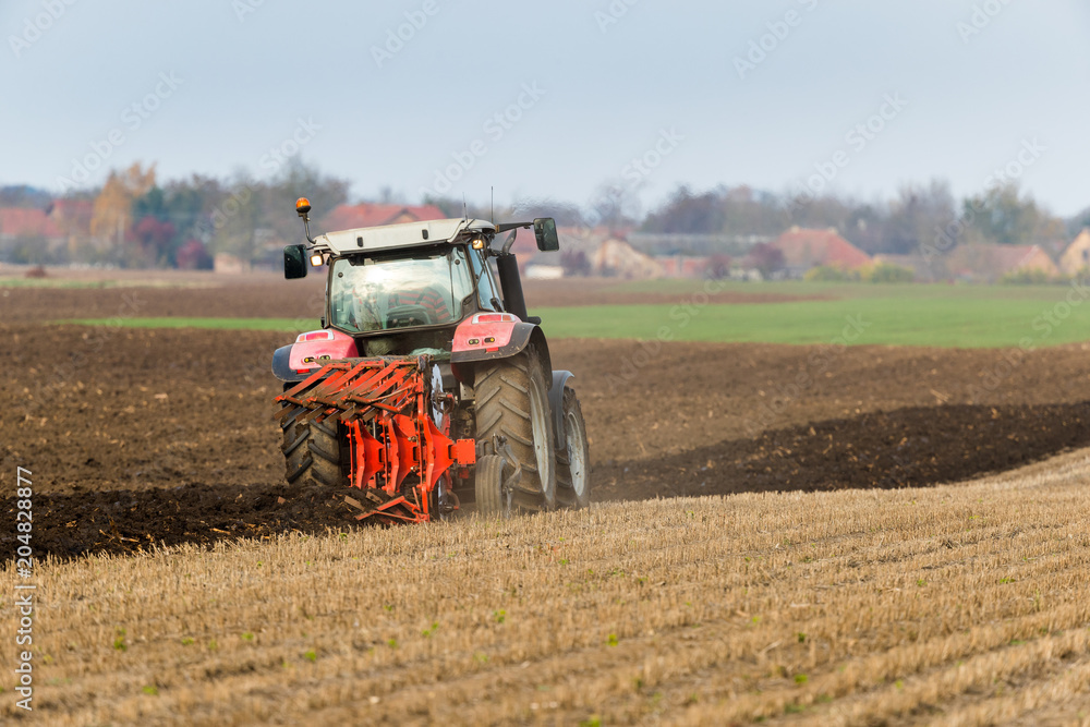 Fototapeta premium Farmer plowing stubble field