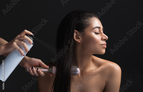 Profile of calm lady making hairdo. Hairdresser using hairspray and comb. Isolated on background
