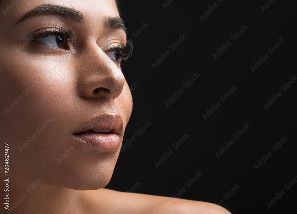 Fototapeta premium Close up of woman appearance with long eyelashes looking aside. Copy space in right side. Isolated on black background