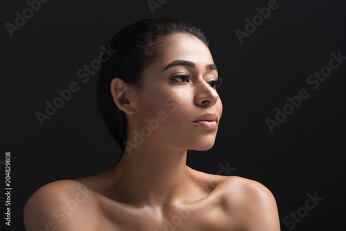 Portrait of african girl showing nice facial features and nude upper body. She is thoughtful. Isolated on black background