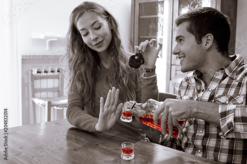 young woman refuses to drink alcohol and she has car keys in hand. responsible drinking and diving concept. black and white image with only liquor in colorful highlighting. photo