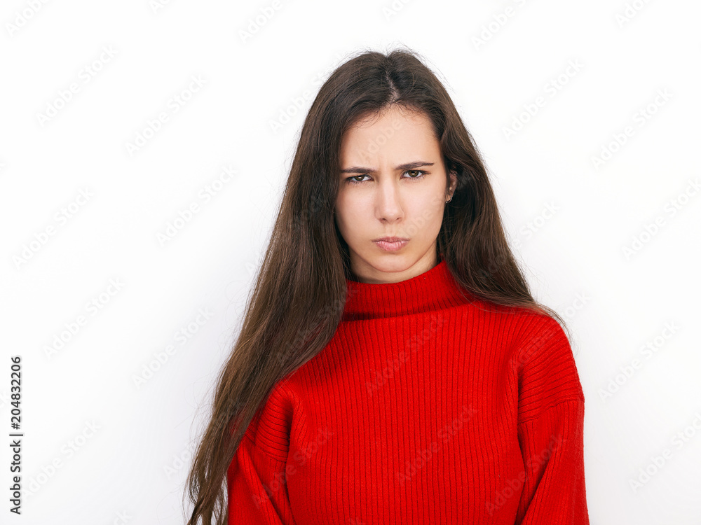 Young beautiful brunette woman in red sweater showing suspicious emotion posing against white background Young beautiful brunette woman in red sweater showing suspicious emotion posing against white background