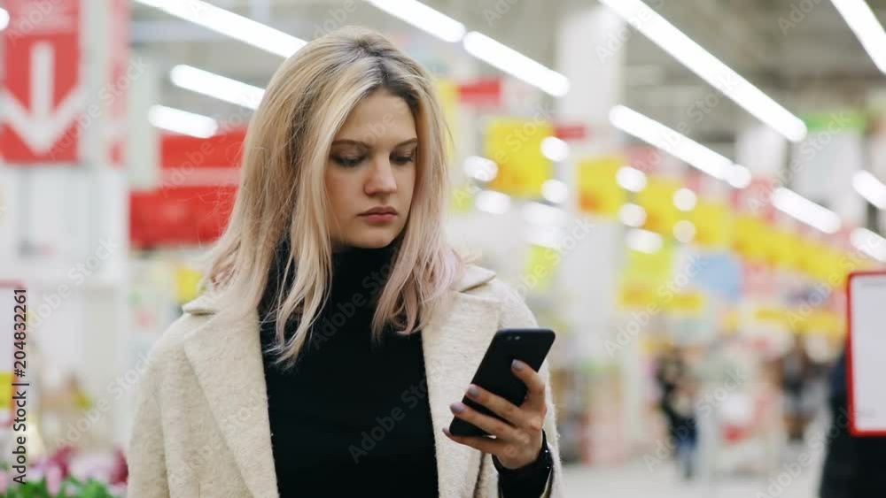 serious confident businesswoman using smartphone in supermarket on blur background looking at screen checking notification pretty woman holding mobile browsing 3G internet connceting communicating serious confident businesswoman using smartphone in supermarket on blur background looking at screen checking notification pretty woman holding mobile browsing 3G internet connceting communicating