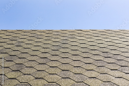 Textured roof of building with shingle covering against clear blue sky. Copyspace