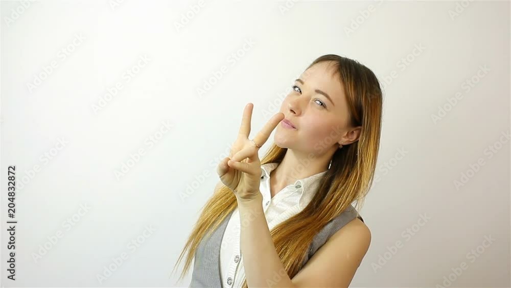 Beautiful young woman showing victory sign and smiling. Beautiful young woman showing victory sign and smiling.