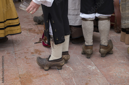 A man wearing traditional costume is pouring a bottle of cider